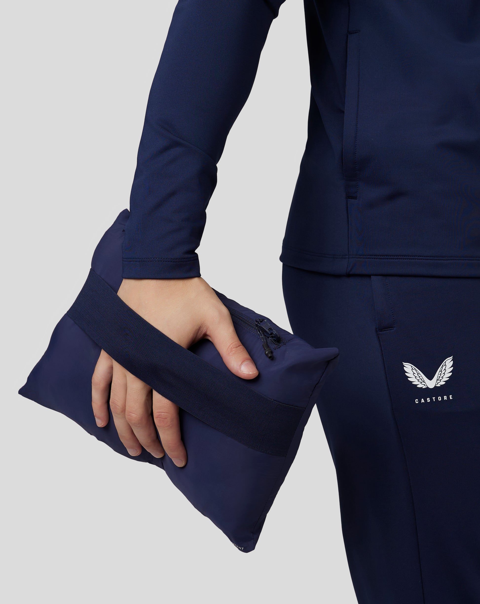 Navy Castore travel lightweight puffer jacket sleeve with a zipped side pocket and Castore logo.