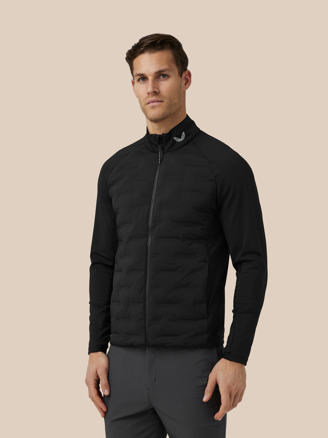 Man in black stand collar jacket with full zip and visible Castore branding at the collar and upper back.