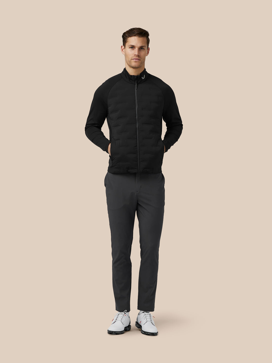 Front view of a man wearing a black quilted hybrid jacket with a stand collar and zip front.