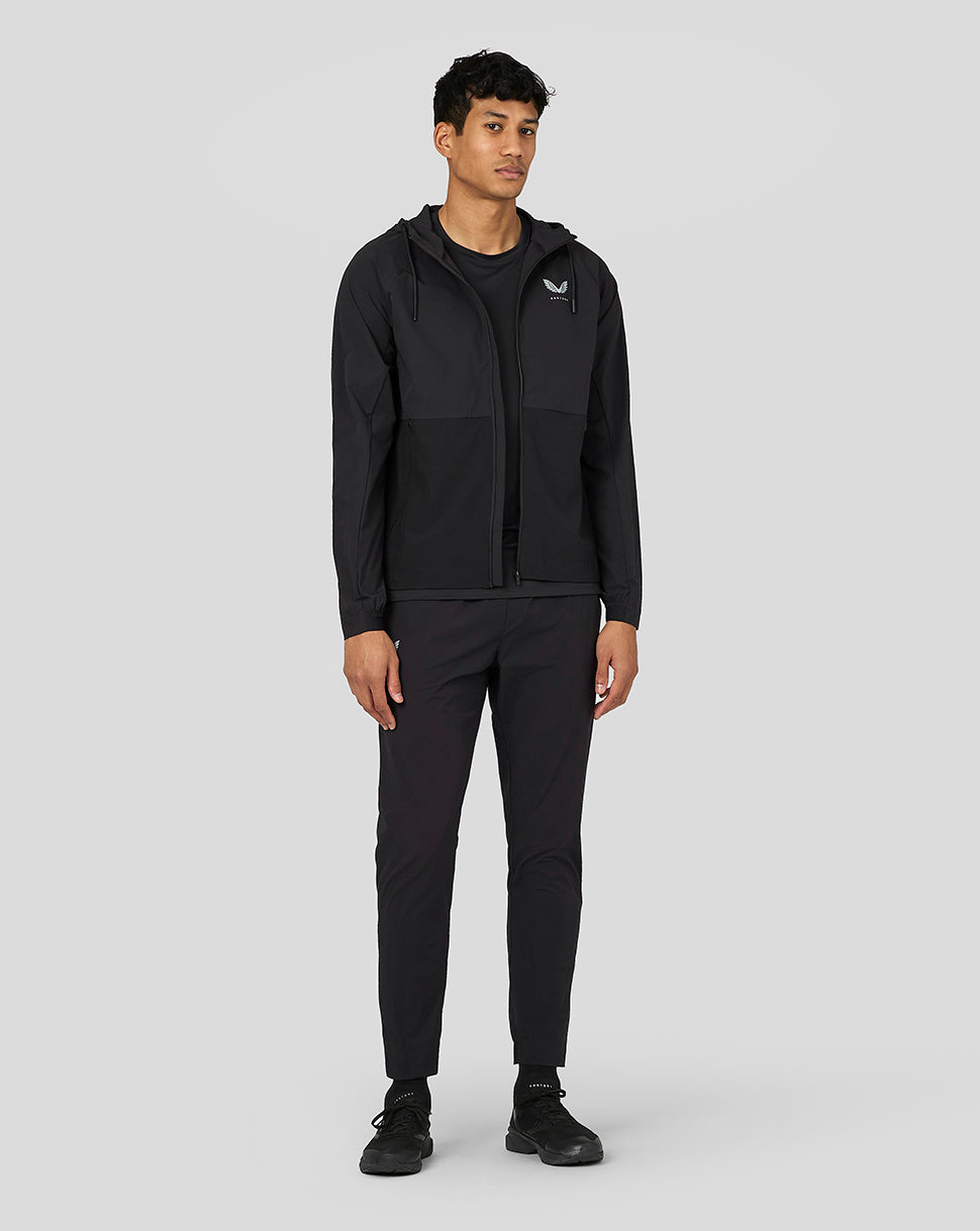 Male model wearing black Castore lightweight woven jacket with hood and full front zip