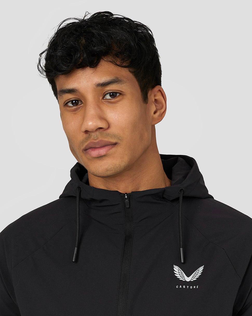 Close up of a male model wearing a black Castore lightweight woven jacket with hood and front zip