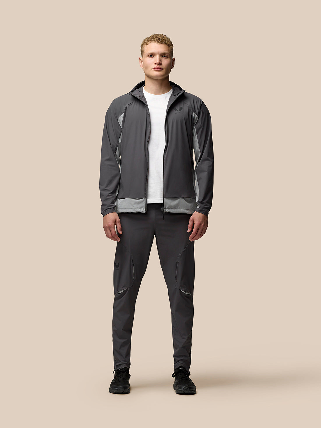 Full body shot of a man in a grey zip hooded jacket with matching joggers.