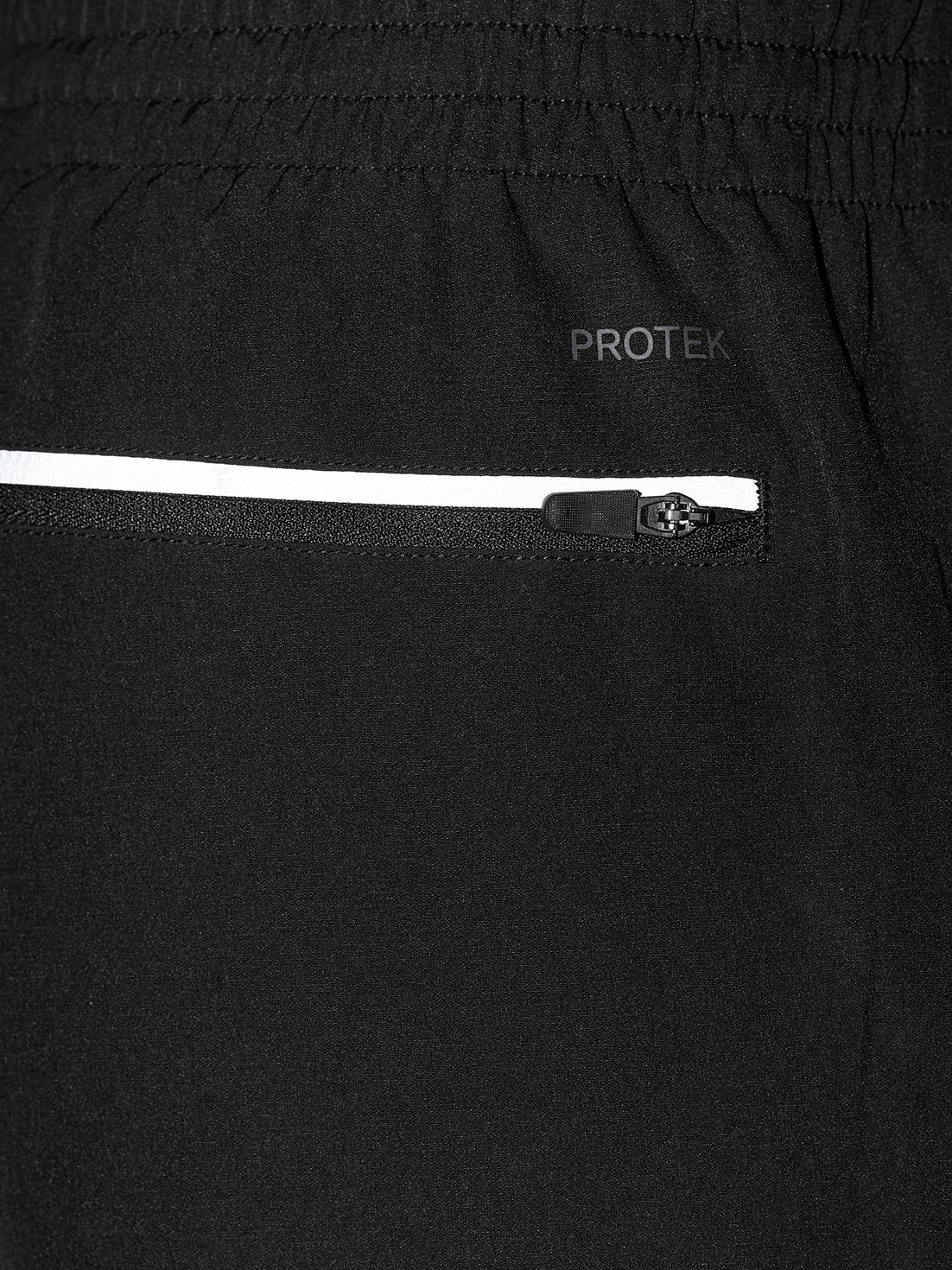 Close up of black jogger fabric showing a reflective zipper pocket and PROTEK branding