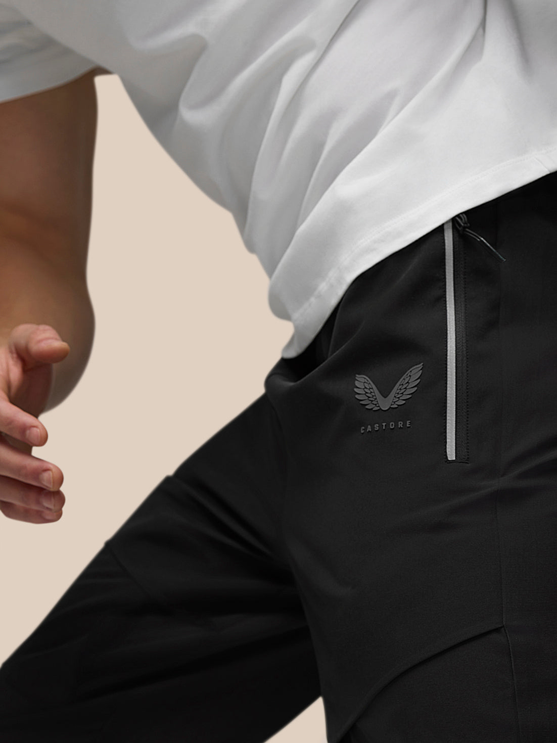 Close-up of Castore wing logo and side zipper on black joggers.