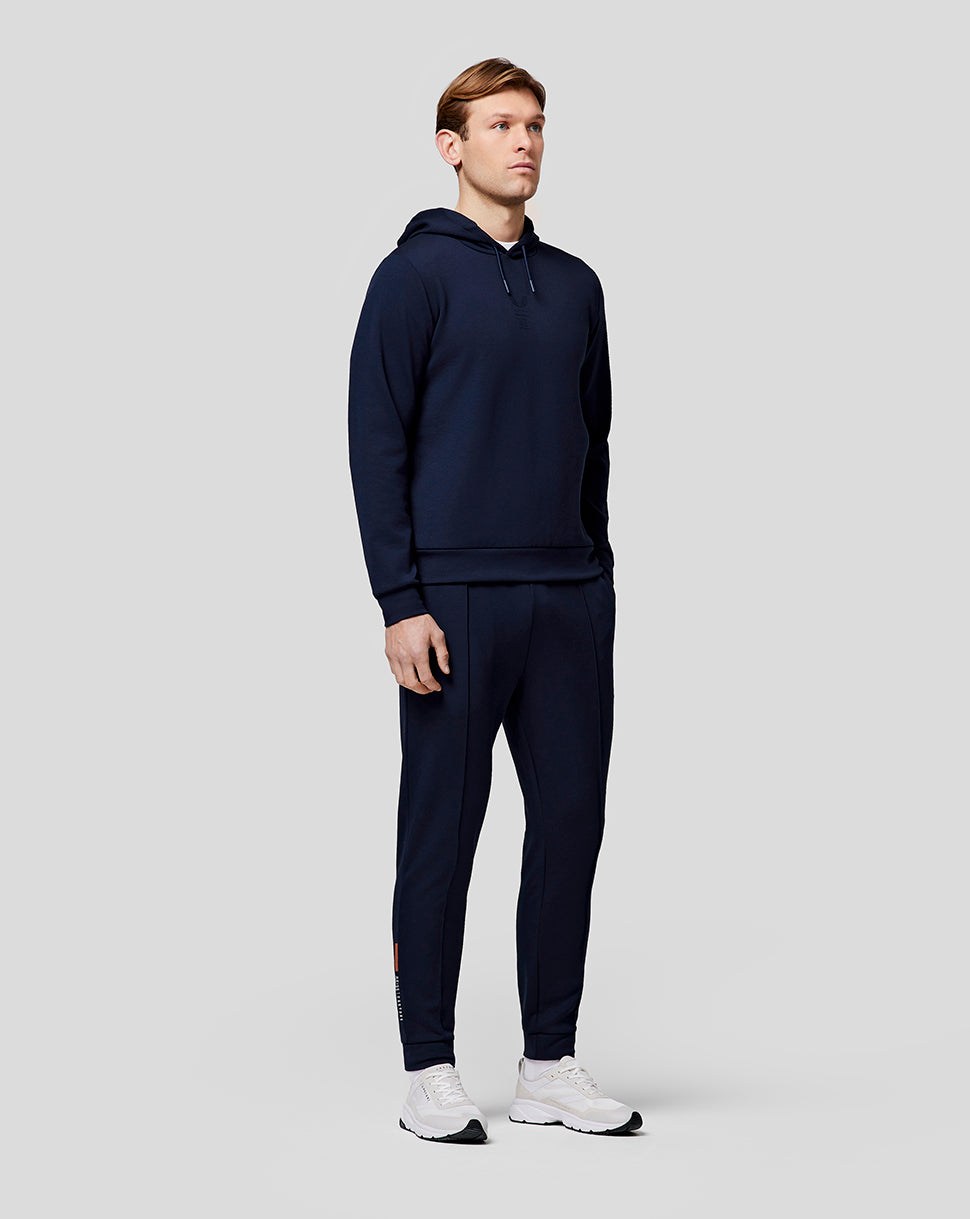 Male model in navy hoodie and matching recovery joggers, showing tapered fit and streamlined athletic look