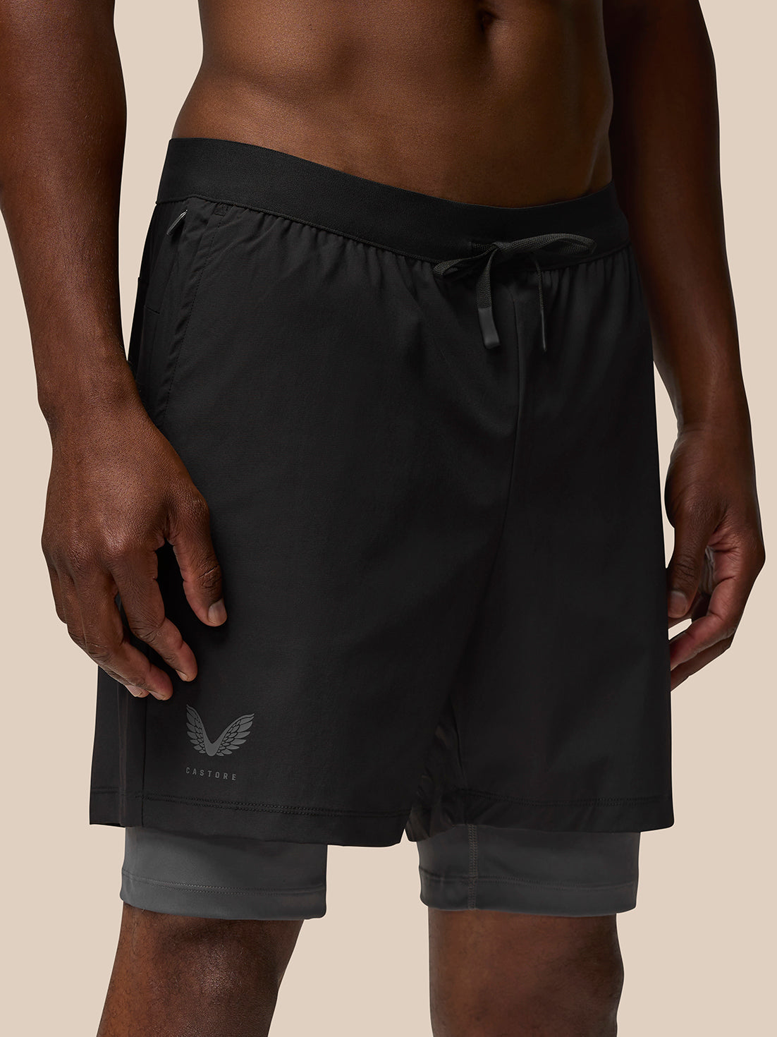 Close-up of black Flow 2-in-1 shorts waistband with drawstring and inner gray layer visible; Castore logo on front left leg