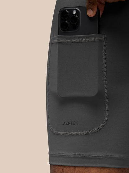 Close-up of the side pocket on black Flow Training Shorts with a smartphone inside and Aertek branding on the pocket.