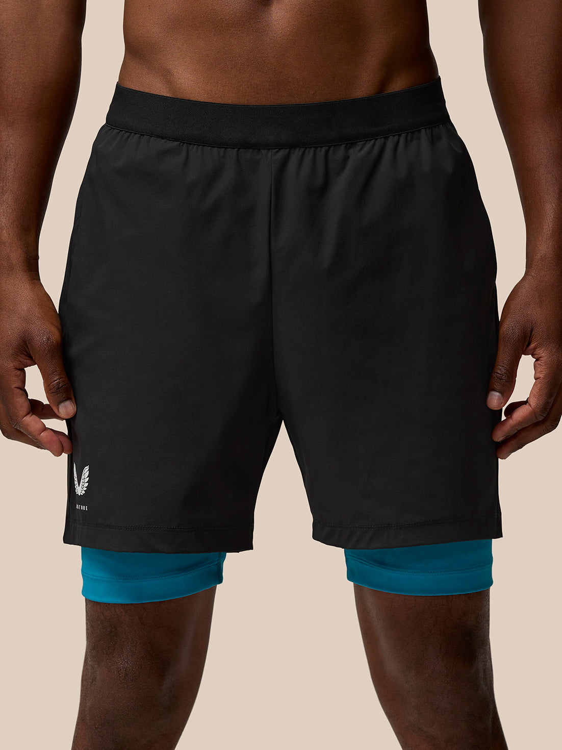 Front view of Flow Training Shorts in black with teal underlayer peeking from beneath the hem and Castore branding on the leg.