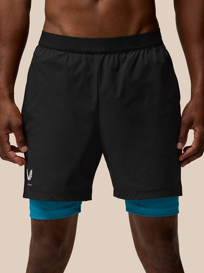 Front view of Flow Training Shorts in black with teal underlayer peeking from beneath the hem and Castore branding on the leg.