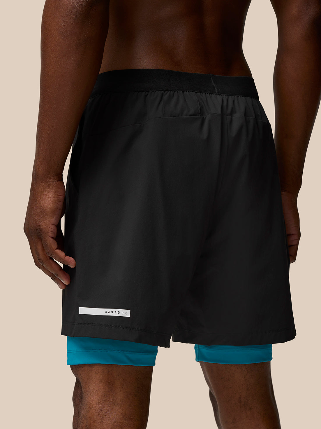 Back view of Flow Training Shorts in black with teal underlayer, Castore branding on right thigh and AerTek branding on left thigh.