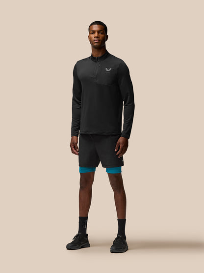 Male model wearing Flow Training Shorts in dark aqua with teal underlayer visible beneath black outer shorts