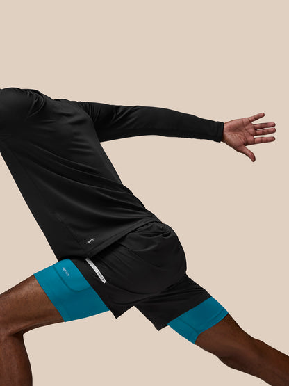 Side view of a runner wearing Flow Training Shorts in black with teal underlayer, AerTek branding on the left thigh.