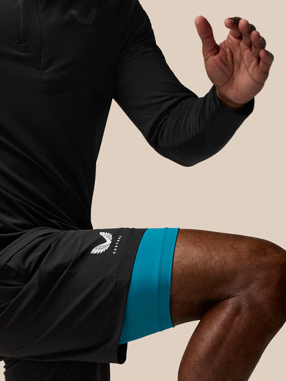 Waist and upper thigh shot of Flow Training Shorts in black with teal underlayer, AerTek branding on left thigh and Castore branding on right thigh.