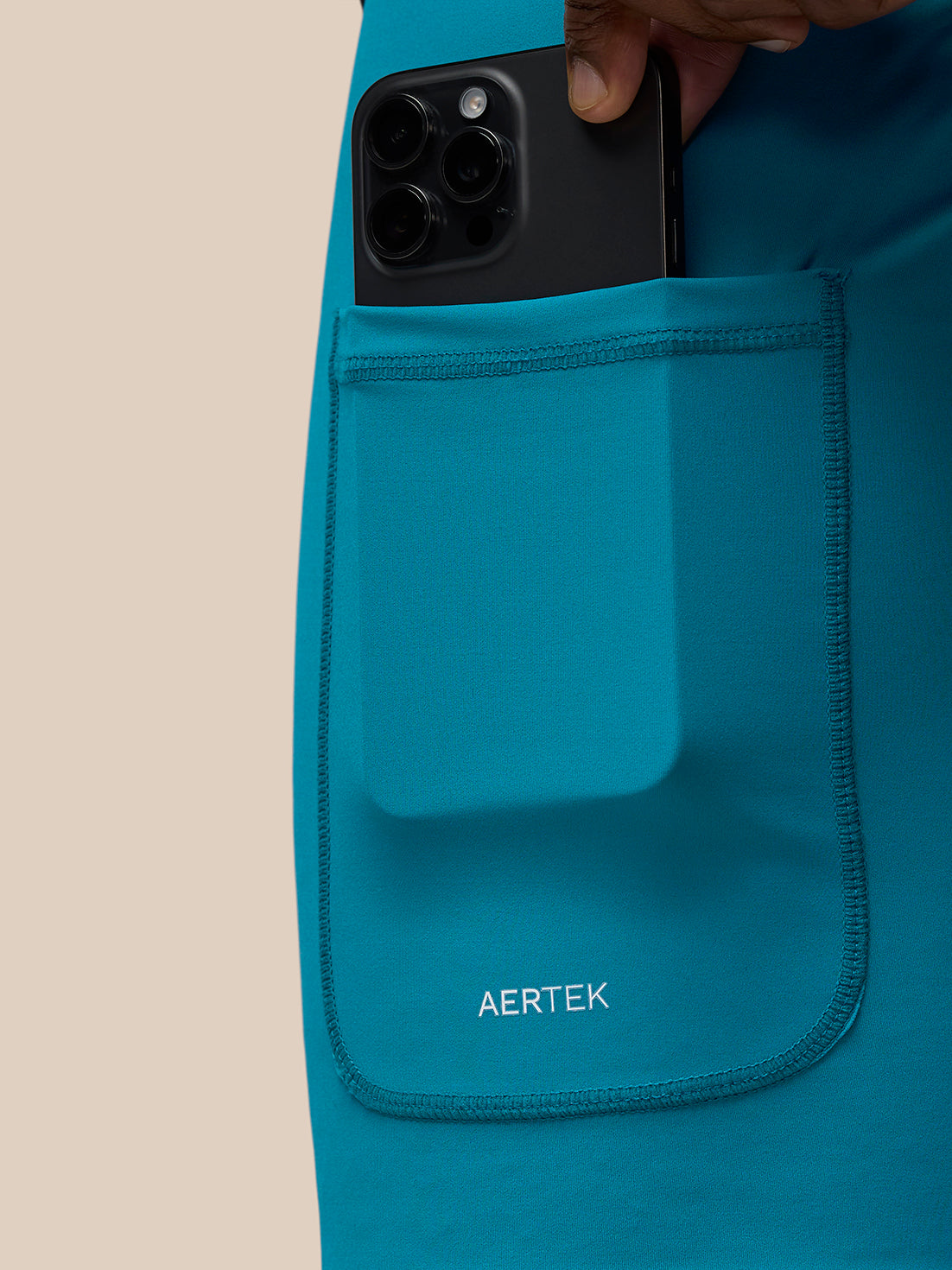 Teal Flow Training Shorts pocket with a phone tucked in and AerTek branding
