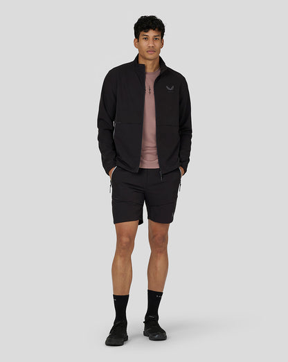Full-body shot of a man wearing a black zip jacket, pink shirt, and black Flex Woven Cargo Shorts.
