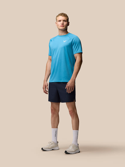 Male model in bright blue athletic top and navy Adapt Training 7 inch shorts