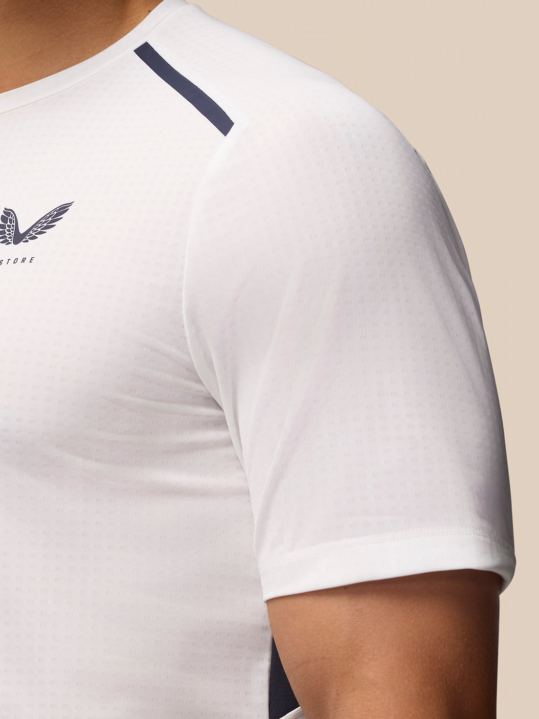 Close-up of white Apex Training T Shirt with navy shoulder stripe and Castore logo on chest.