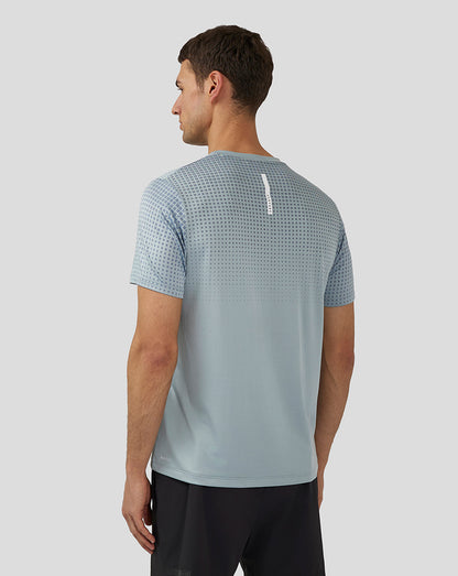 Back view of stone blue T shirt with dotted upper back pattern and a white vertical reflective stripe.