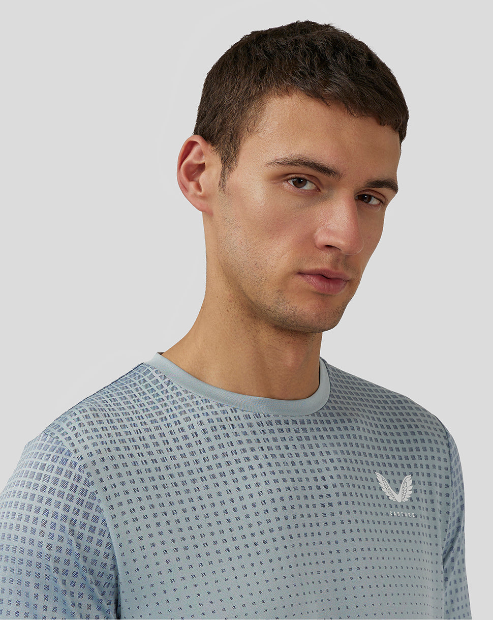 Close up of male model wearing Stone Blue Flow Short Sleeve Knit T Shirt showing dotted pattern on shoulder with Castore logo on chest