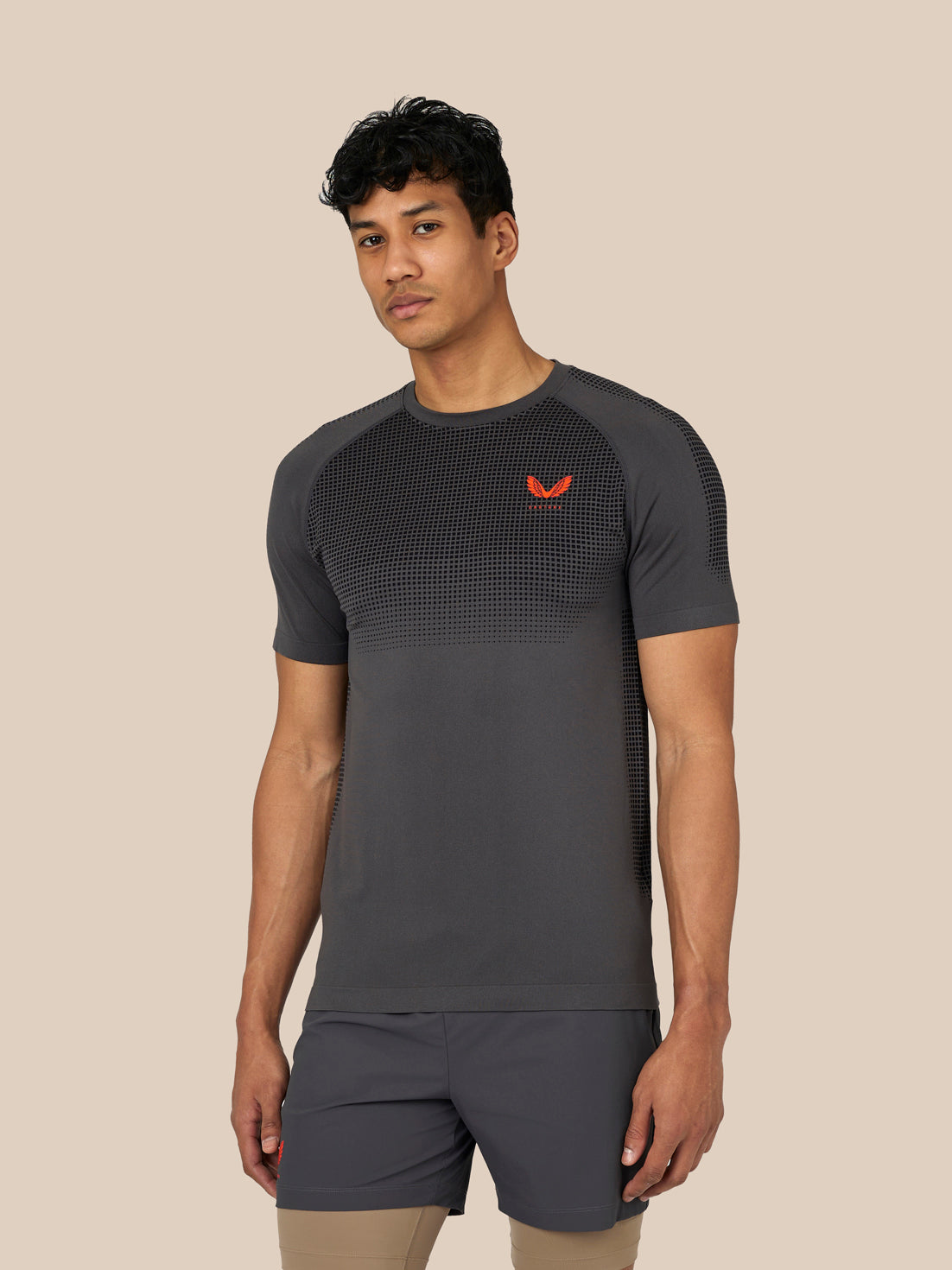 Male model wearing grey Flow Training T Shirt with seamless knit and dotted chest panel and front Castore logo