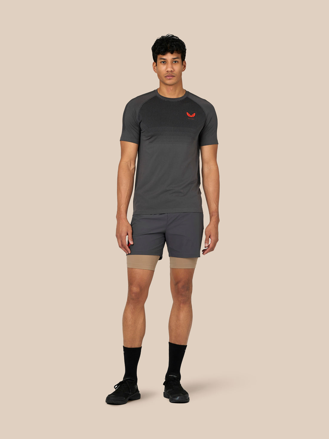 Male model wearing dark grey Flow Training T-Shirt with a dotted chest panel and raglan sleeves.