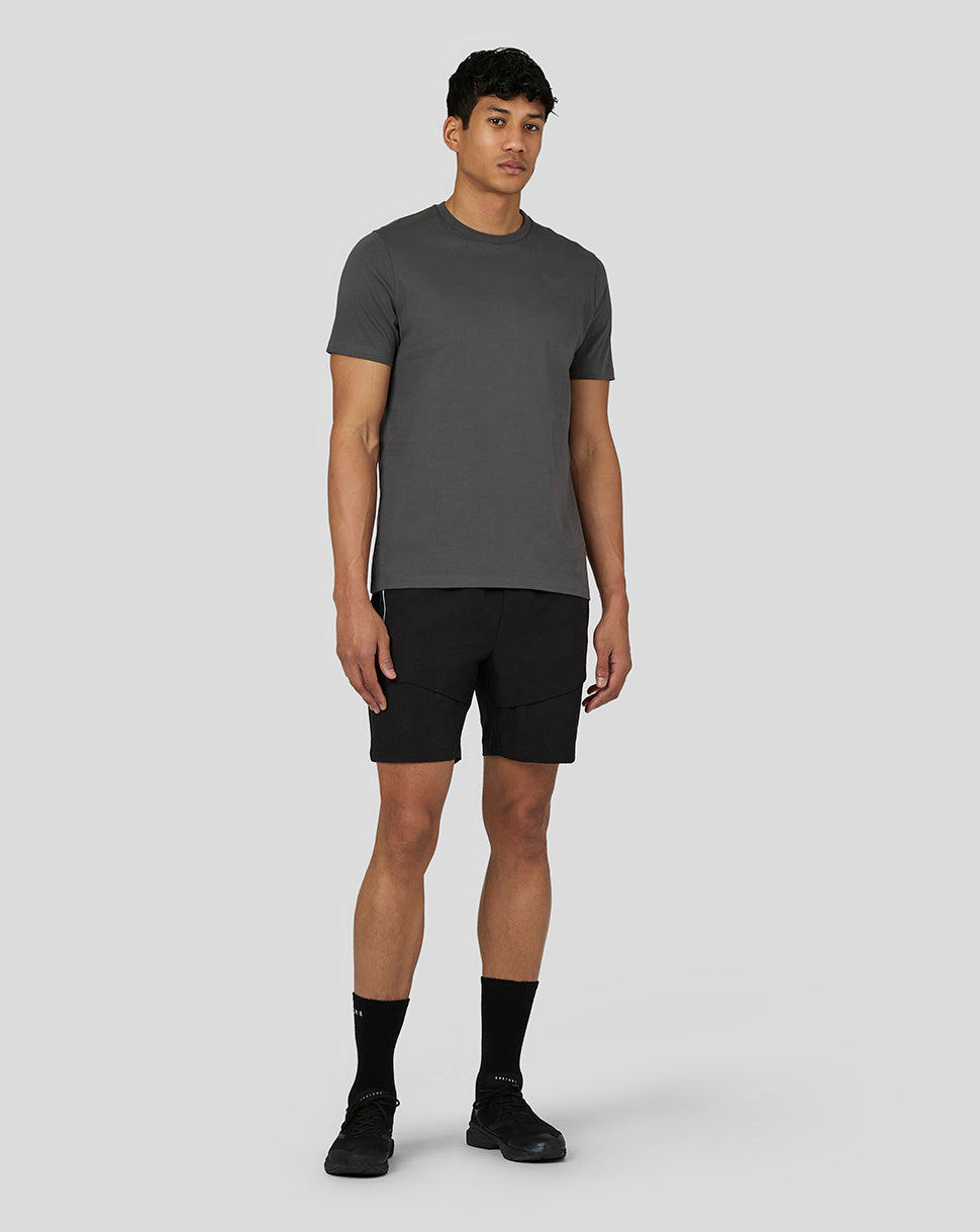 Three quarter view of a male model in gunmetal gray Castore Flex Short Sleeve T Shirt with black shorts