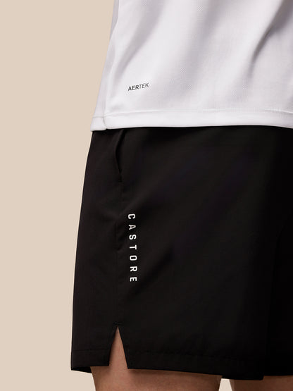 Close up of white Adapt Short Sleeve Graphic T Shirt hem with Aertek branding and black shorts with vertical Castore lettering