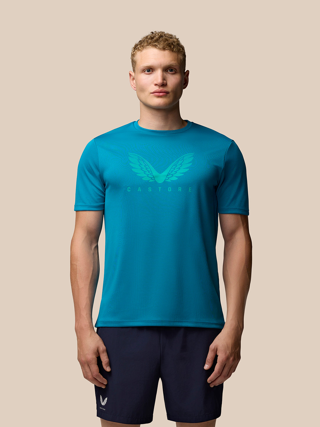 Teal Adapt Short Sleeve Graphic T Shirt worn by a model with wings logo on the chest.