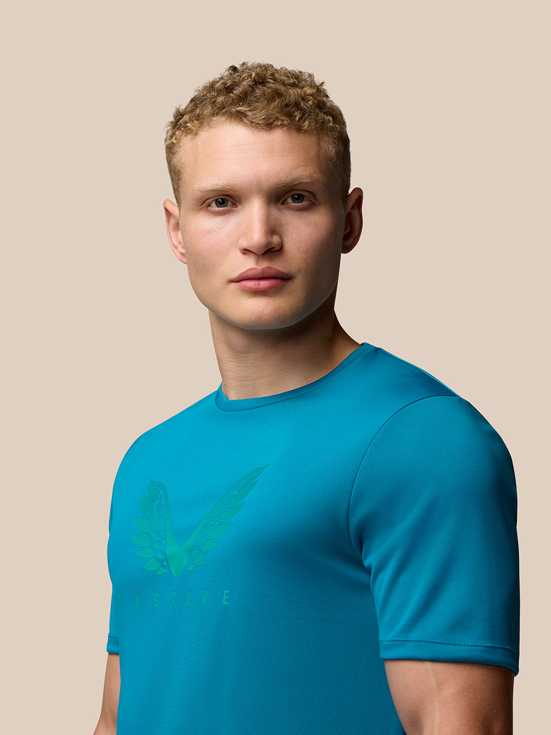 Profile view of a man in turquoise Adapt Short Sleeve Graphic T-Shirt featuring the wing graphic