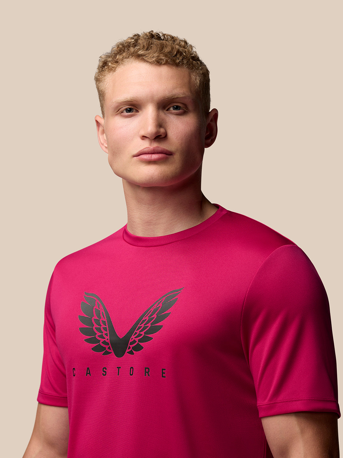 Male model wearing pink Adapt Training T-Shirt with Castore wings graphic on chest