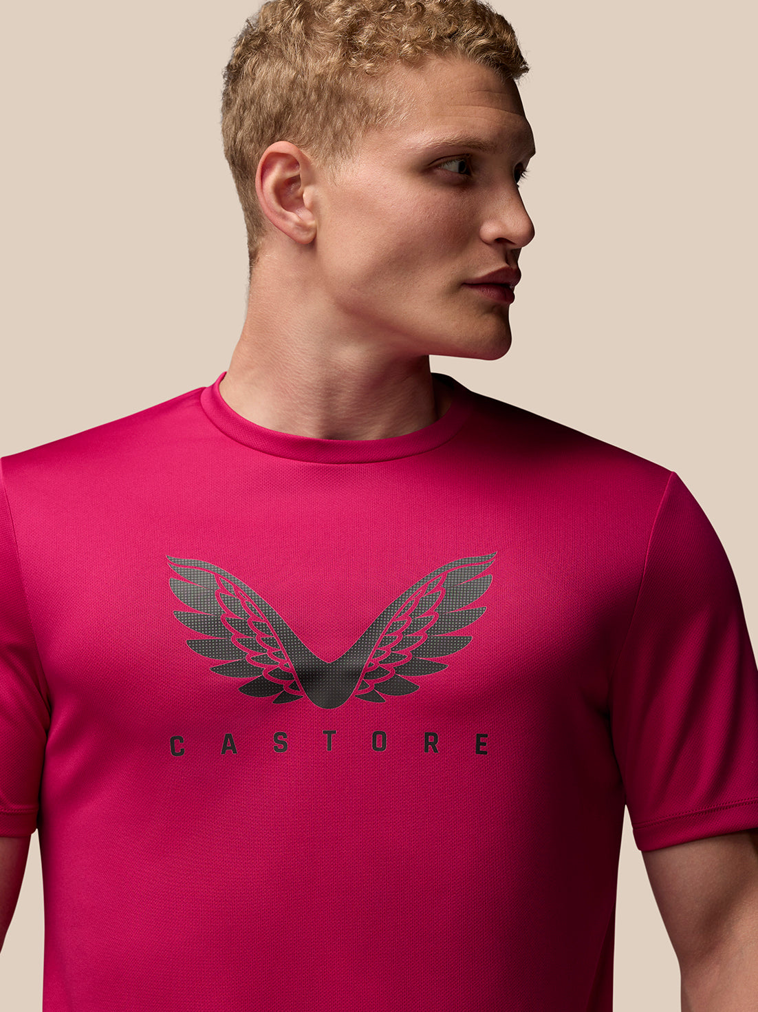 Male model wearing pink Adapt Training T-Shirt with Castore wings graphic on the chest.