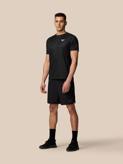Three quarter view of a man in black Adapt Training T Shirt with all over print and branding on the chest.