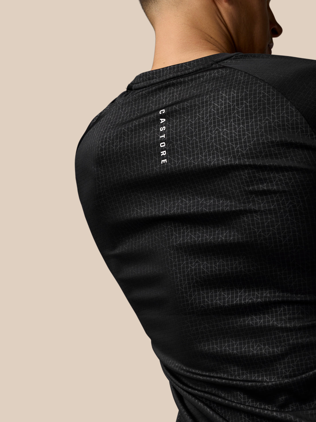 Rear view of black Adapt Training T-Shirt showing vertical Castore branding on shoulder and geometric print.