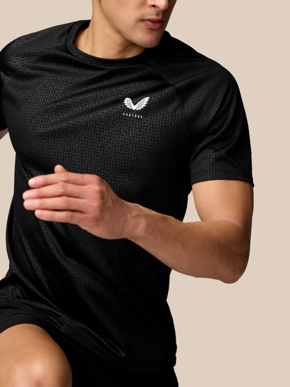 Side-angle view of male in black Adapt Training T-Shirt with Castore logo on chest and subtle all-over pattern.
