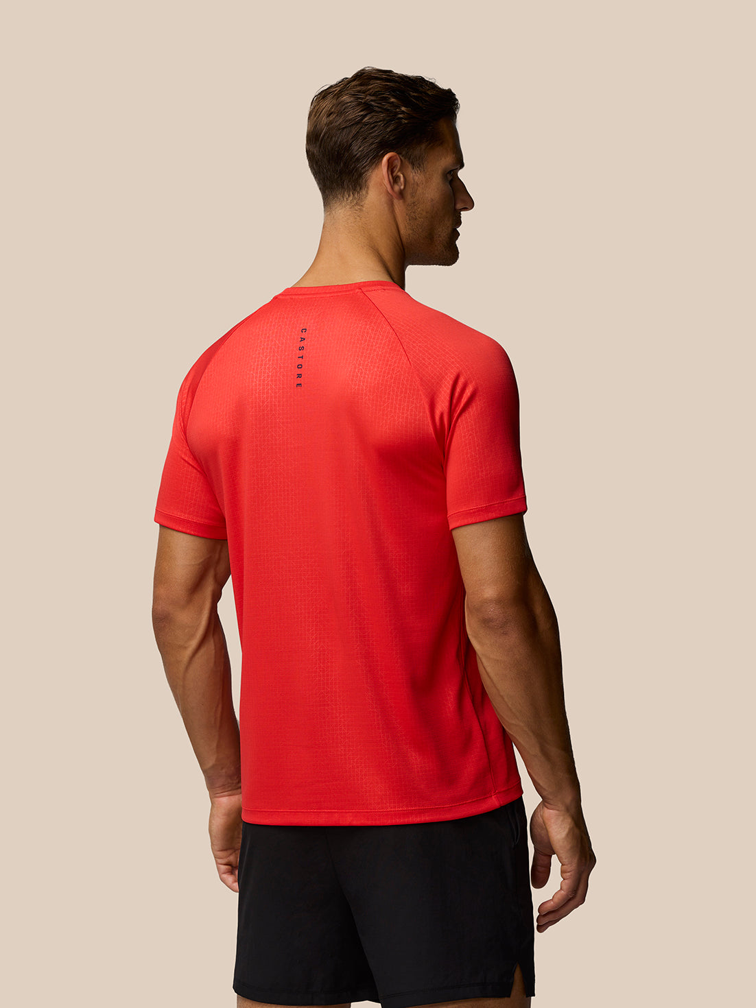Back view of red Adapt Training T-Shirt with all over print and a vertical Castore branding mark along the spine