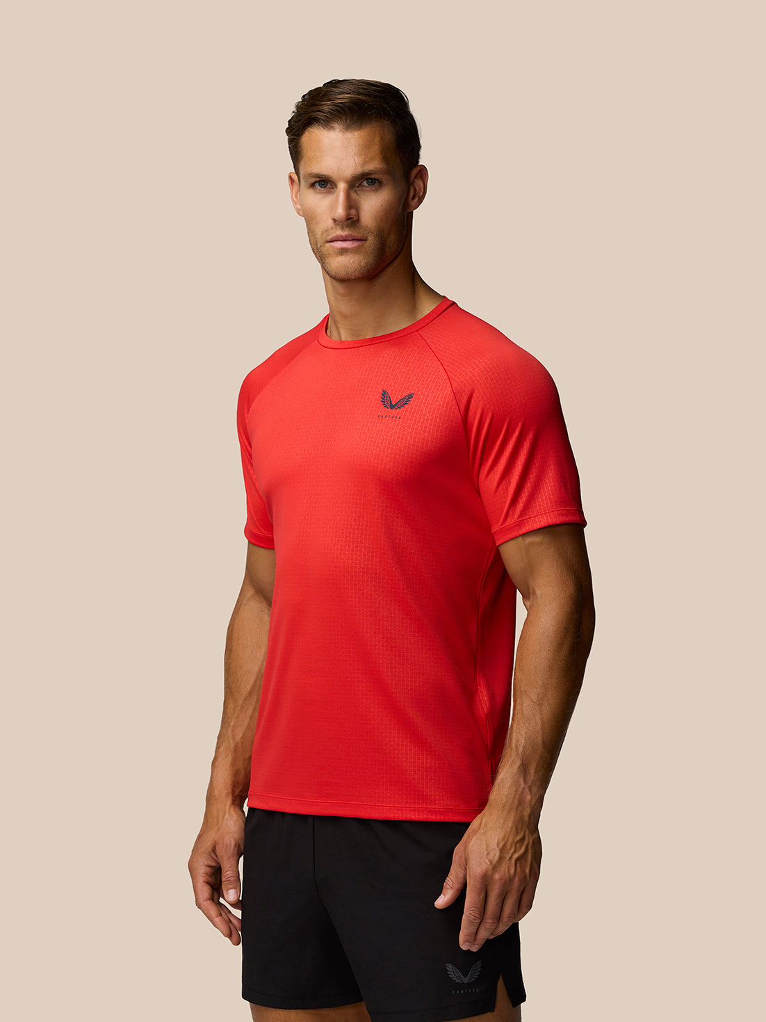 Male model wearing red Adapt Training T-Shirt with Castore logo on chest and subtle all over grid pattern