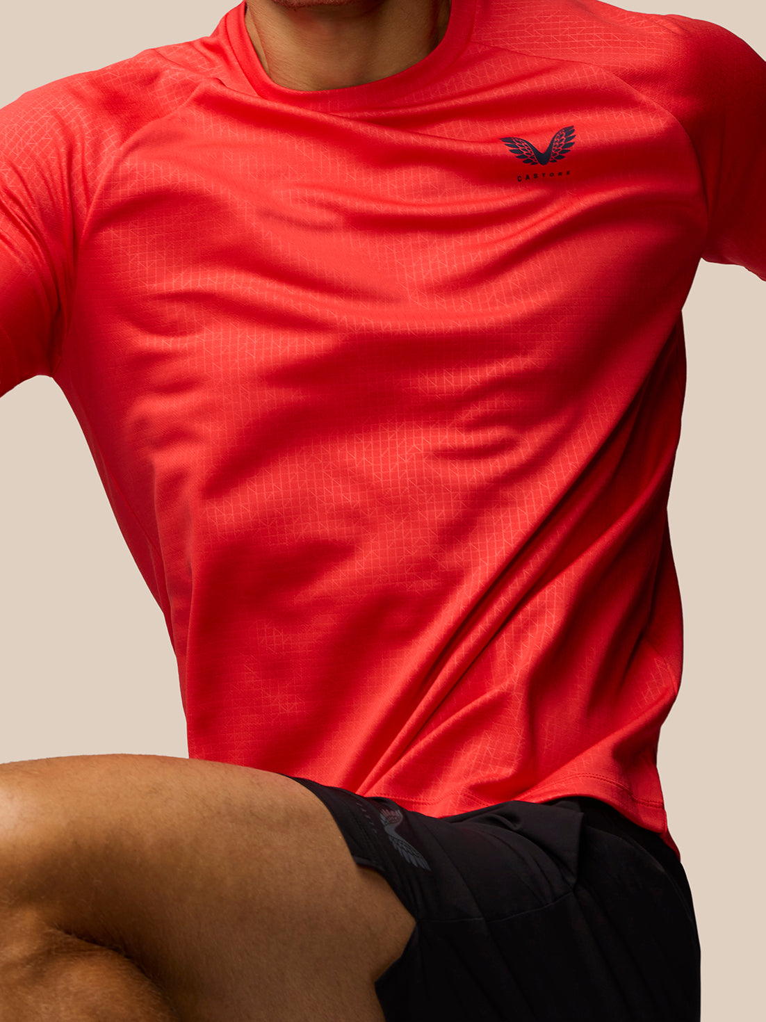 Close-up of red Adapt Training T-Shirt chest area showing Castore logo and subtle geometric print