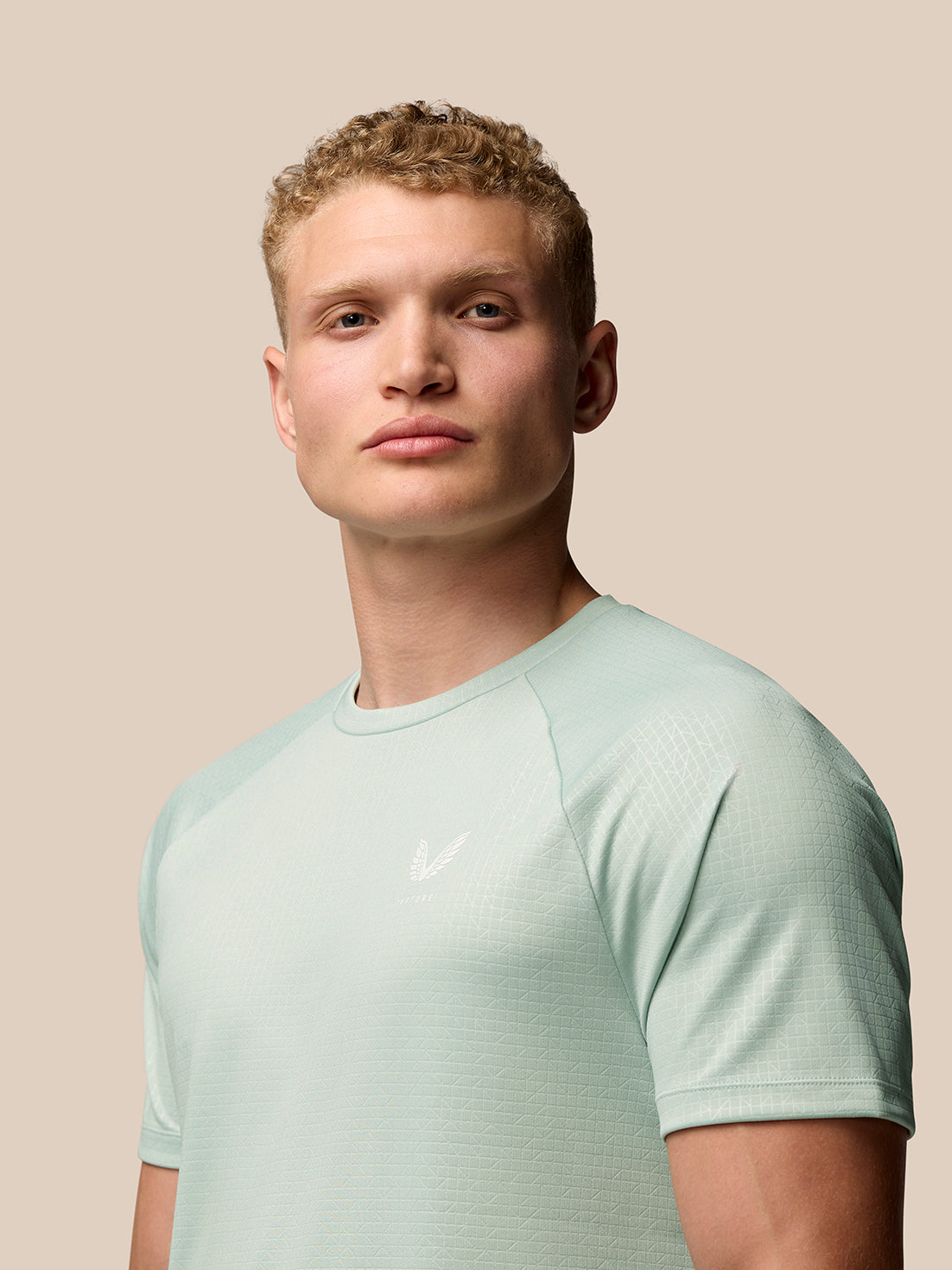 Male model wearing mint green Adapt Training T Shirt with a subtle geometric pattern and Castore logo on the chest