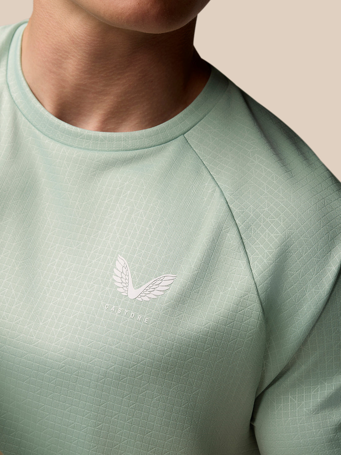 Close-up of mint green Adapt Training T Shirt showing a textured geometric pattern and Castore logo on the chest