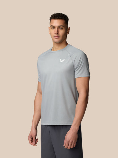 Front three quarter view of a model wearing Adapt Training T Shirt in mid grey with small Castore logo on the chest.