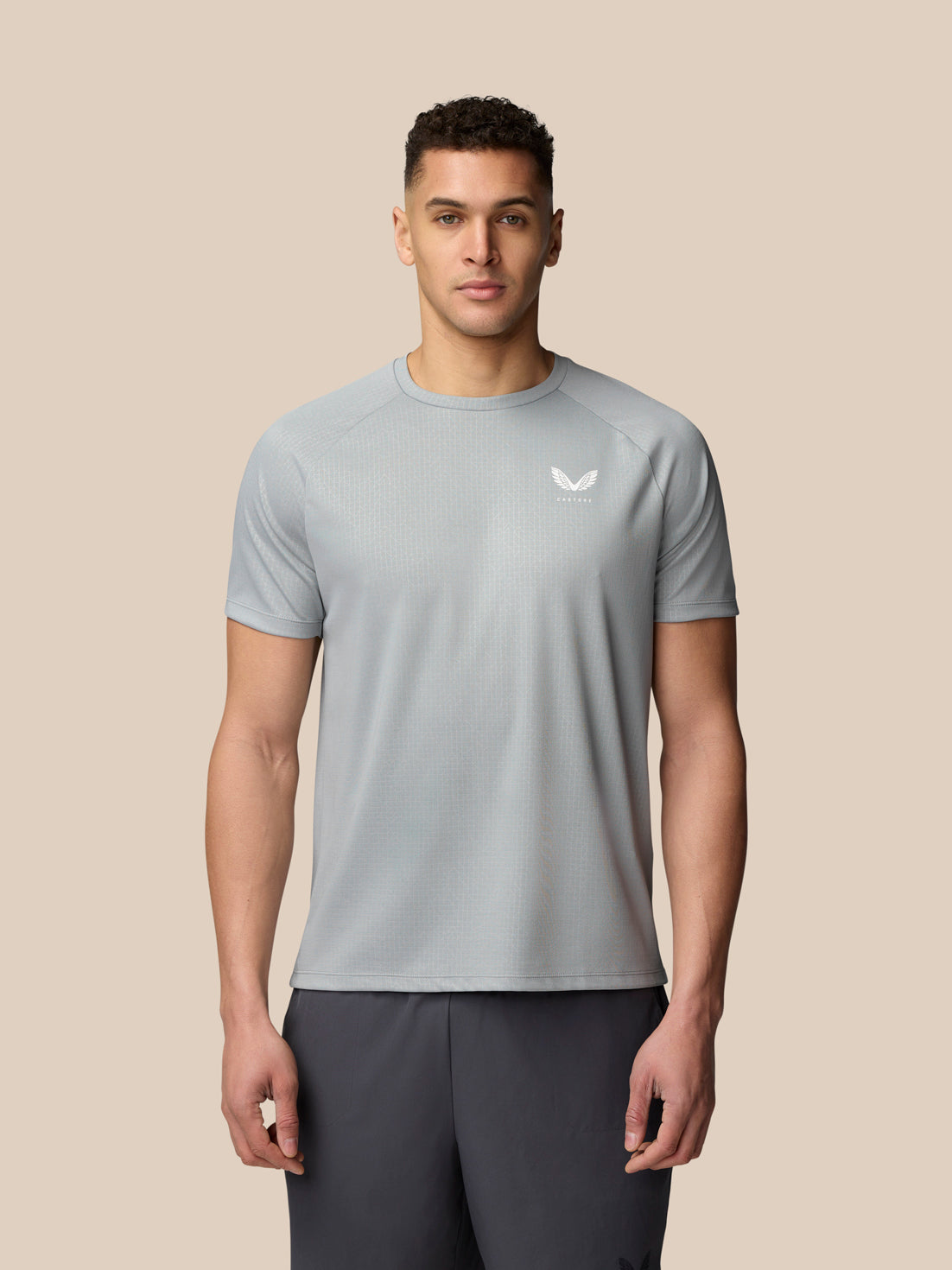 Front view of a man wearing light grey Adapt Training T Shirt with a white Castore logo on the chest and subtle all over print