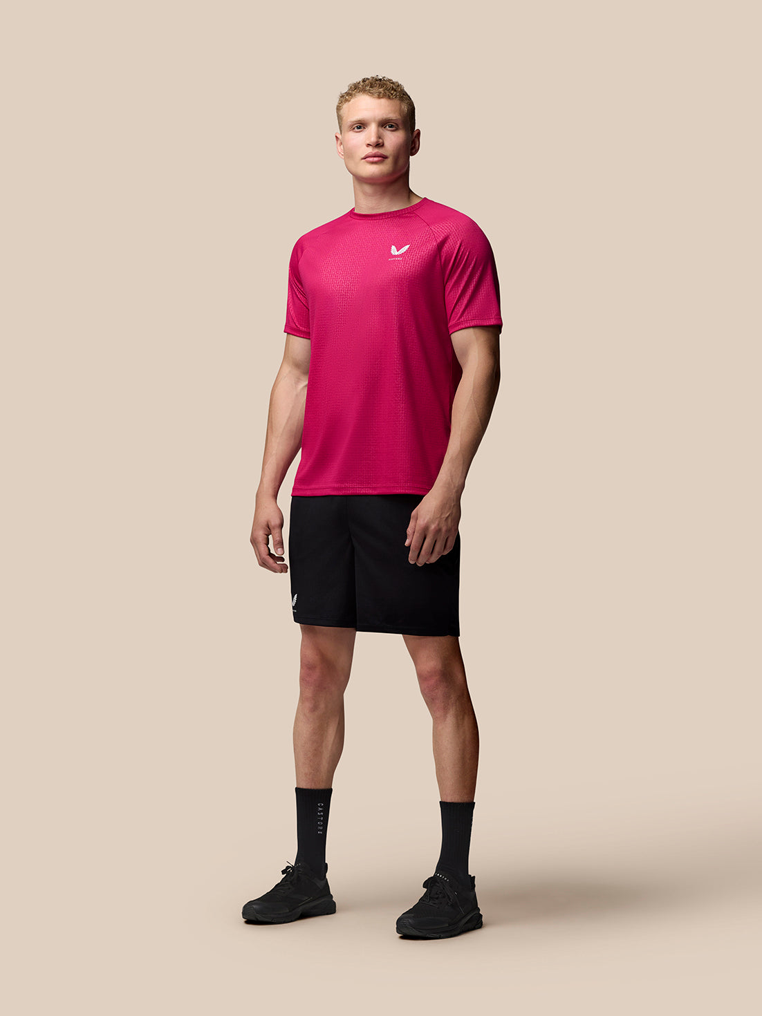 Male model wearing bright pink Adapt Training T Shirt with a geometric pattern and Castore logo on the chest.