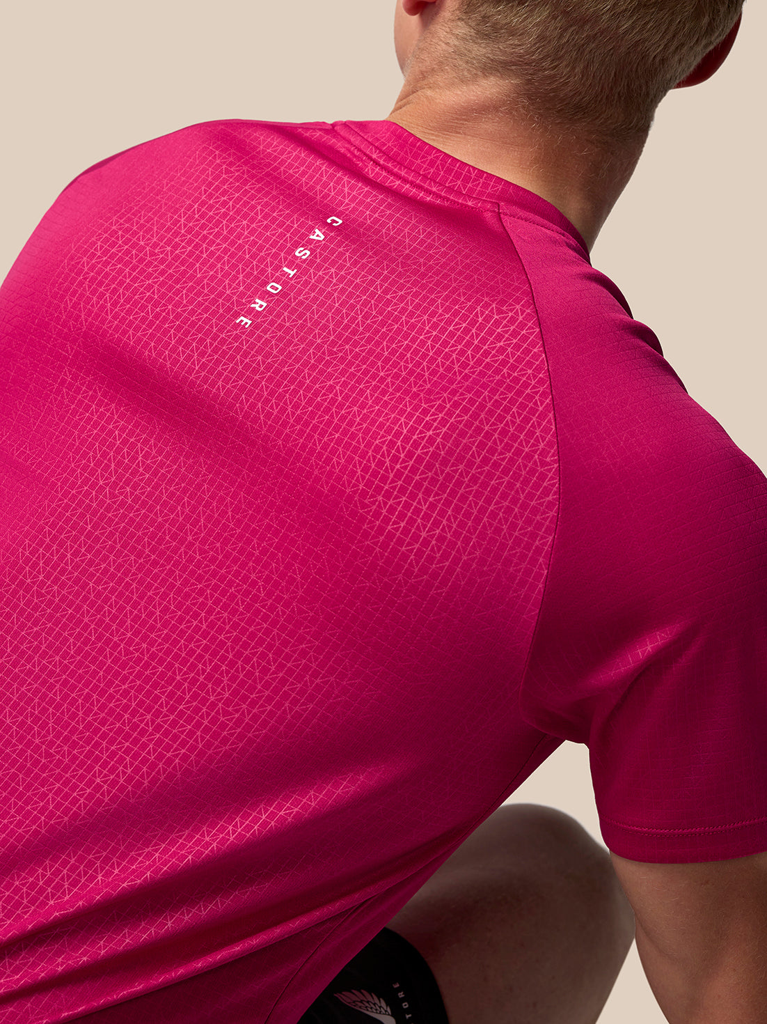 Back view of pink Adapt Training T Shirt showing vertical CASTORE lettering on the upper back with a geometric pattern across the shoulders