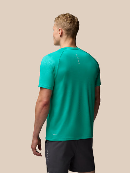 Back view of a man wearing a bright aqua Adapt Training T shirt with geometric pattern, Castore branding on left chest and upper back, Aertek at lower back