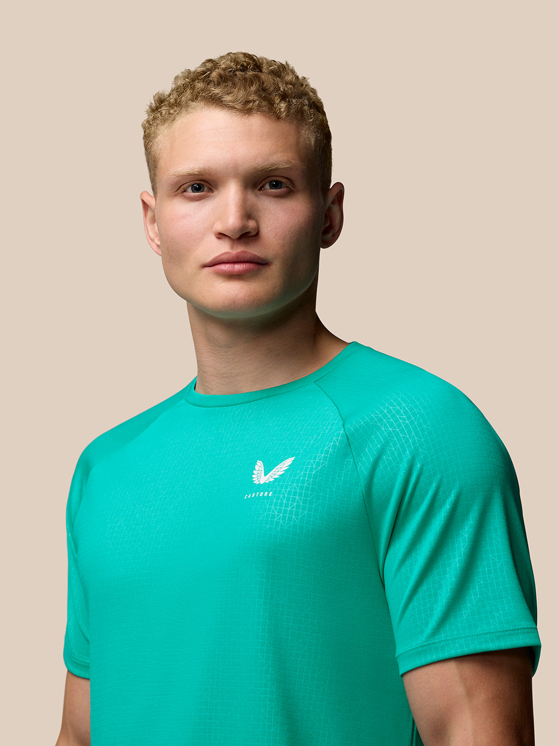 Male model wearing bright aqua Adapt Training T-Shirt with a subtle geometric pattern and Castore logo on the left chest