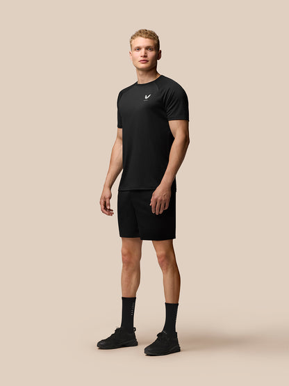 Full body shot of male model in black Adapt Short Sleeve T Shirt with Castore logo on chest and black shorts