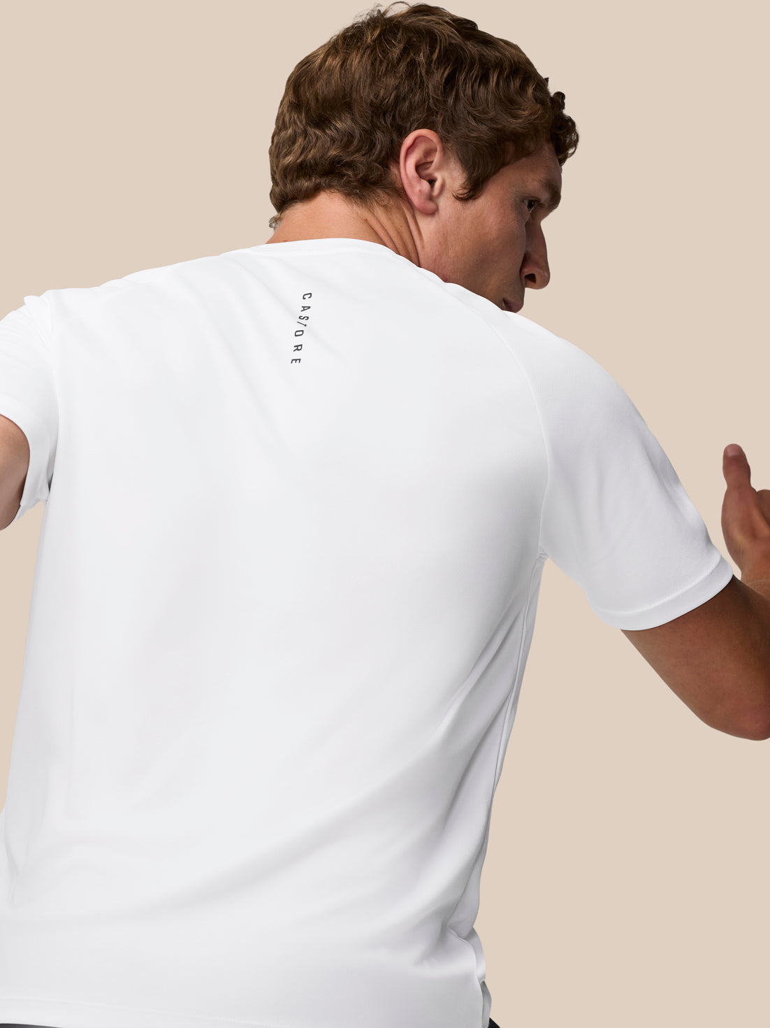 Back view of a person in a white Adapt Training T-Shirt with vertical Castore branding on the upper back.