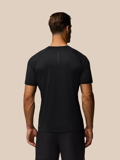 Back view of a man wearing a black Adapt Training T Shirt with Castore branding along the upper back.
