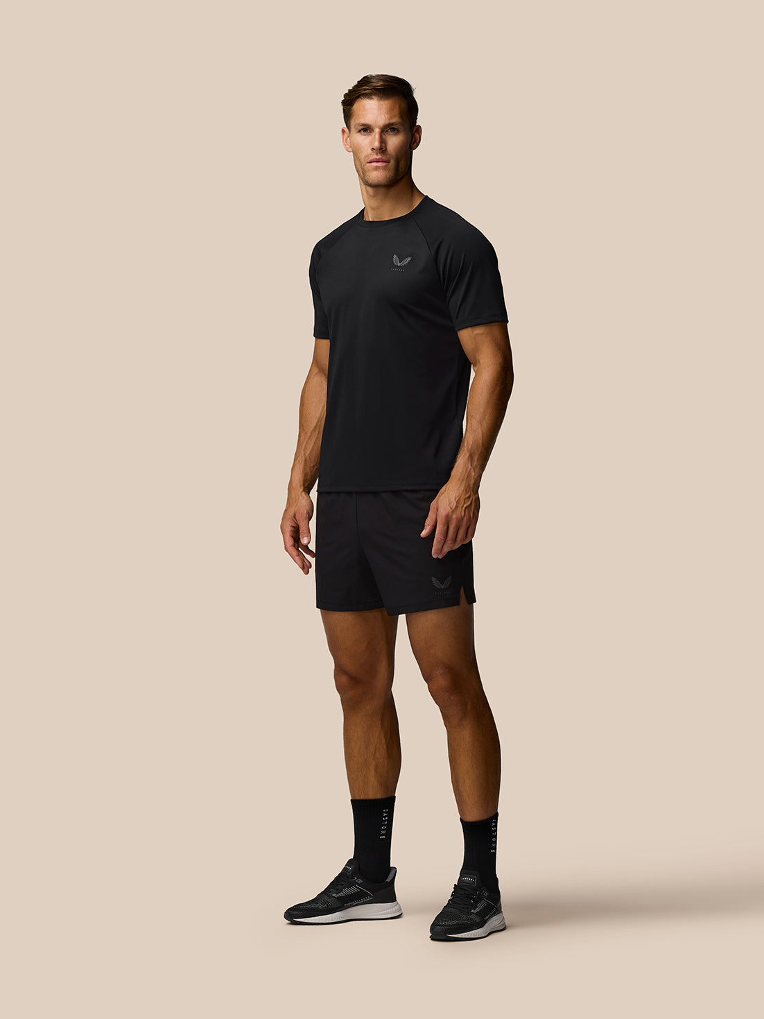 Male model in black athletic shirt and shorts with Castore logo on the chest and on the shorts.