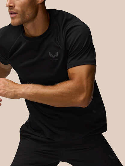 Close-up action shot of a man in a black athletic T shirt with Castore logo on the chest.